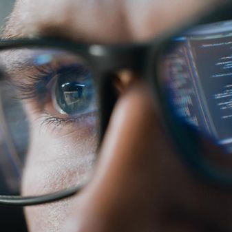 Close-up Portrait of Software Engineer Working on Computer, Line of Code Reflecting in Glasses.